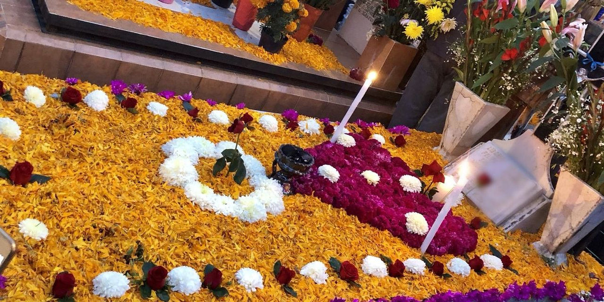 A grave in the Mixquic cemetery covered in marigold petals, magenta cockscomb, white chrysanthemums, and candles for Día de Muertos. Carrie's own photo.